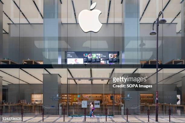 Pedestrian walks past the American multinational technology company Apple store and logo in Hong Kong.