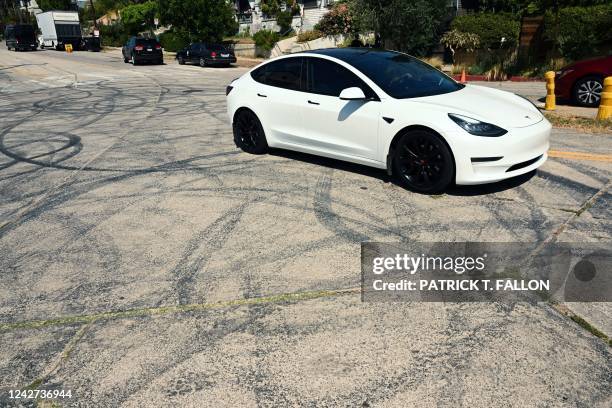 Tesla electric vehicle drives past tire skid marks from other drivers doing burnouts and "donuts" on Bellevue Ave near Bob's Market where area...