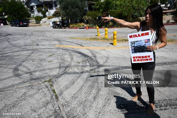 Local resident and protester with Street Racing Kills points to tire skid marks from drivers doing burnouts and "donuts" on Bellevue Ave as area...