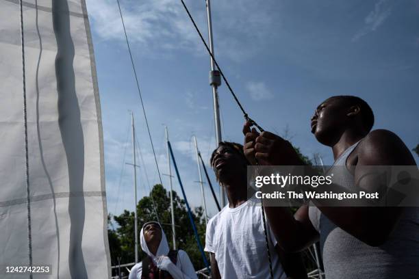 Black teens, including Jayden Hill right, Rondell Franklin center, and Cyrus Chambers leftt, rig up 12 sailboats to take out onto the Annapolis Bay...