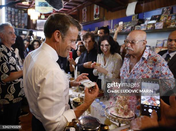 France's President Emmanuel Macron looks at an audio tape as Boualem Benhaoua , owner of the disco Maghreb Shopin, mythical label of rai music, and...