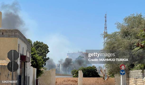 Smoke billows as rival Libyan groups exchange fire in the capital Tripoli, on August 27, 2022. - The fighting broke out in various districts of...