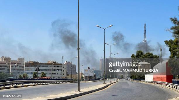 Smoke billows as rival Libyan groups exchange fire in the capital Tripoli, on August 27, 2022. - The fighting broke out in various districts of...