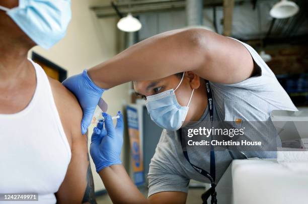 Jeremy Oyague, right, a registered nurse with The Los Angeles Department of Public Health, administers a COVID booster at a vaccination clinic to...