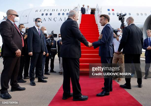 French President Emmanuel Macron shakes hands with Algeria's President Abdelmadjid Tebboune before his departure at Algiers airport, in Algiers, on...