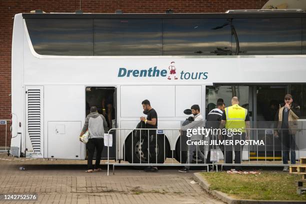 Asylum seekers board a bus inside the gates of the registration and application center in Ter Apel on August 27, 2022. - Hundreds of asylum-seekers...