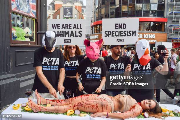 Activists wearing animal masks "dine" on an activist covered in fake blood during the protest in Leicester Square. The action, marking the World Day...