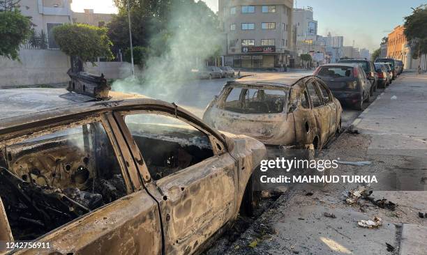 Damaged vehicles are pictured in a street in the Libyan capital Tripoli on August 27 following clashes between rival Libyan groups. - Clashes between...