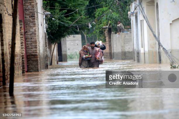 Displaced people wade through a flooded area in Peshawar, Khyber Pakhtunkhwa, Pakistan on August 27, 2022. Since June, nearly 900 people have died by...