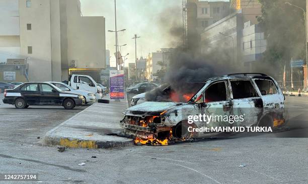 Damaged vehicles are pictured in a street in the Libyan capital Tripoli on August 27 following clashes between rival Libyan groups. - Clashes between...