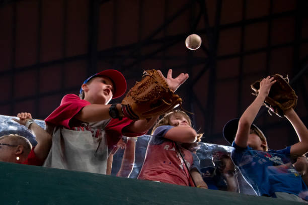 Young Texas Rangers fan gets a baseball from a staff member at Globe Life Field on August 26, 2022 in Arlington, Texas.
