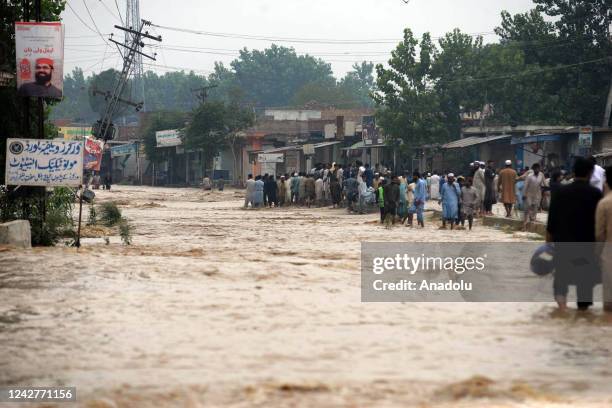 Pakistani people wade through flood water after flash flood hit Charsadda district, in northwest, Khyber Pakhtunkhwa province, Pakistan on August 28,...