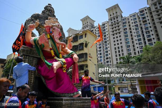 Devotees carry an idol of elephant-headed Hindu deity Ganesha during a procession ahead of the Ganesh Chaturthi festival in Mumbai on August 28, 2022.