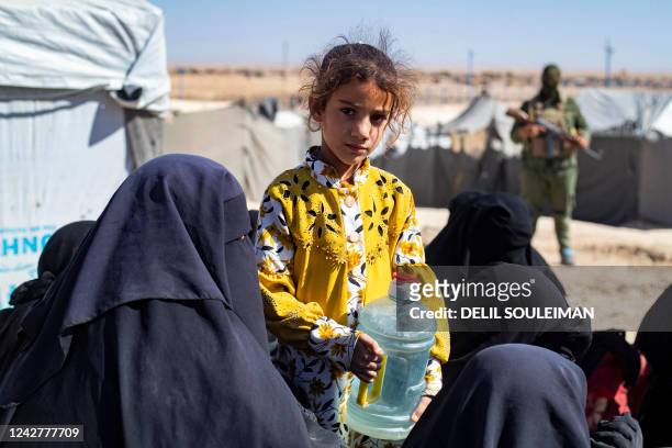 Girl looks on while holding a water container as members of the Syrian Kurdish Asayish security forces inspect tents at the Kurdish-run al-Hol camp,...