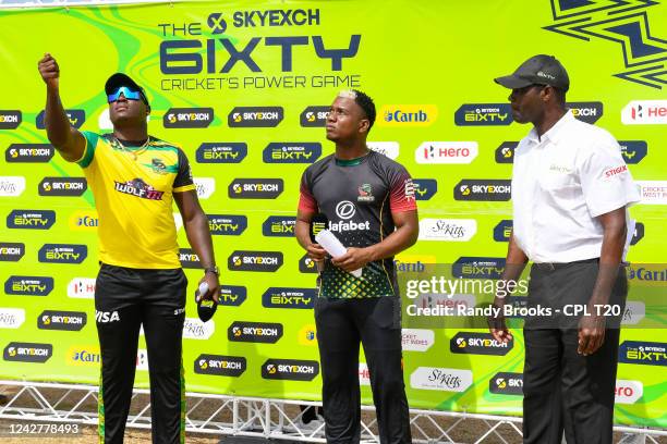 Rovman Powell of Jamaica Tallawahs toss the coin as Evin Lewis of Saint Kitts & Nevis Patriots and match referee Reon King look on during the 2022...