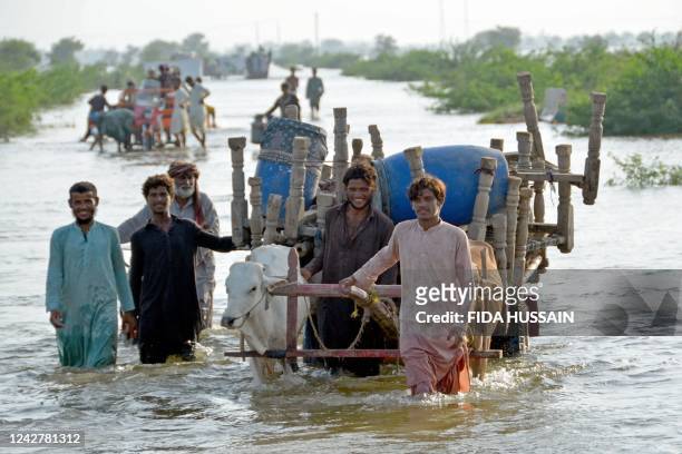 Stranded people along with their belongings wade through a flooded street after fleeing from their flood hit homes following heavy monsoon rains at...