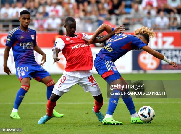 Reims' Malian midfielder Kamory Doumbia fights for the ball with Lyon's Brazilian forward Tete and Lyon's French defender Malo Gusto during the...
