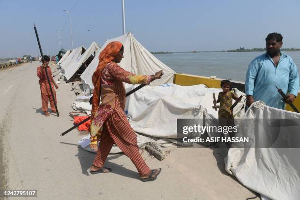 Displaced family prepares to install a tent at a makeshift camp after fleeing from their flood hit homes following heavy monsoon rains in Sukkur,...