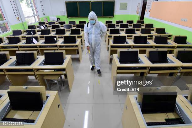 Staff member sprays disinfectant in a classroom at a school ahead of the new semester in Handan in China's northern Hebei province on August 29,...