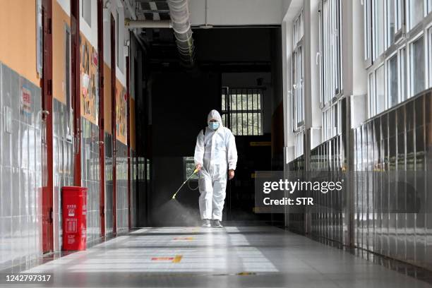 Staff member sprays disinfectant in a corridor at a school ahead of the new semester in Handan in China's northern Hebei province on August 29, 2022....