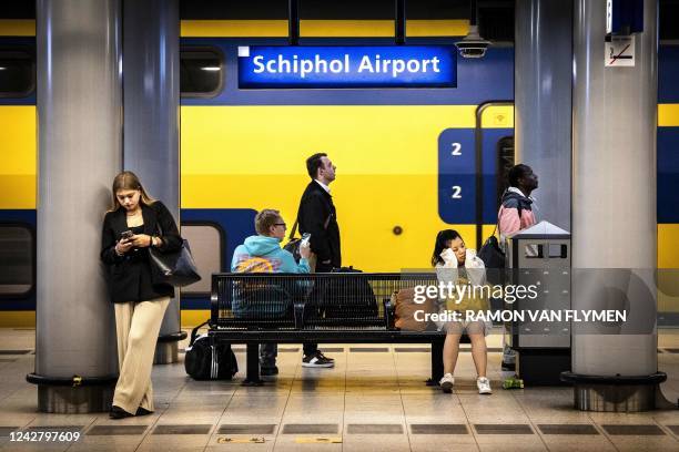 Travellers sit on a platform at the Schiphol Airport train station on August 29 during a Dutch Railways strike. - Due to a 24-hour regional relay...