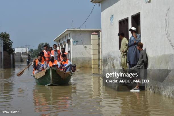 Armed members of Alkhidmat Foundation patrol on a boat at a residential area submerged in floodwater in Nowshera of Khyber Pakhtunkhwa province on...