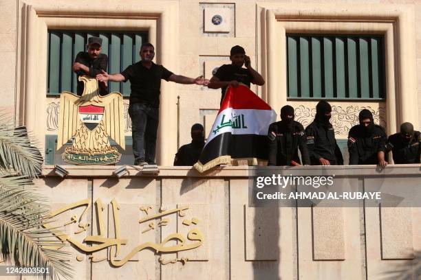 Security forces stand guard as supporters of Iraqi Shiite cleric Moqtada Sadr gather on the balcony of the Government Headquarters in the capital...