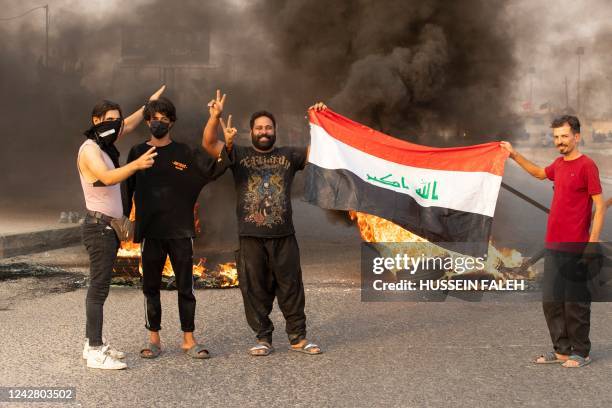 Supporters of Iraqi Shiite cleric Moqtada Sadr pose for a picture on a road blocked with burning tyres during a demonstration in Iraq's southern city...