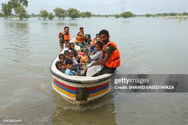 Rescue workers use a boat to drop children back home after school in a flood hit area following heavy monsoon rains in Dera Ghazi Khan district in...