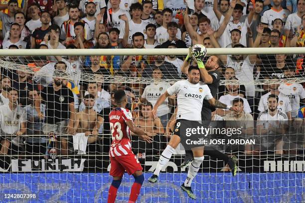 Atletico Madrid's Slovenian goalkeeper Jan Oblak makes a save as he vies with Valencia's Uruguayan forward Maxi Gomez during the Spanish League...