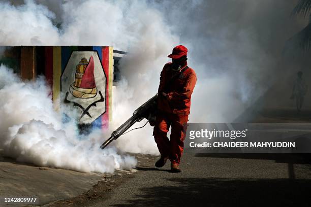 Worker dispenses insecticide with a fogging machine to kill mosquitos spreading dengue fever in Banda Aceh on August 30, 2022.