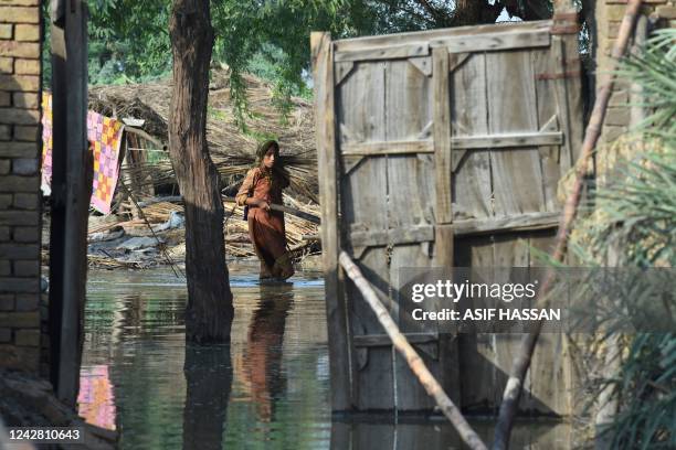 Flood affected woman carries firewood at her flooded house following heavy monsoon rains at Shikarpur in Sindh province on August 30, 2022. - Aid...