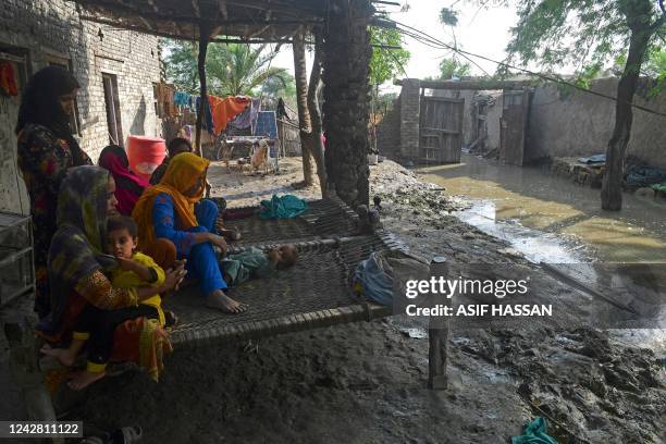 Flood-affected family sits in their partially flooded house at Shikarpur in Sindh province on August 30, 2022. - Aid efforts ramped up across flooded...