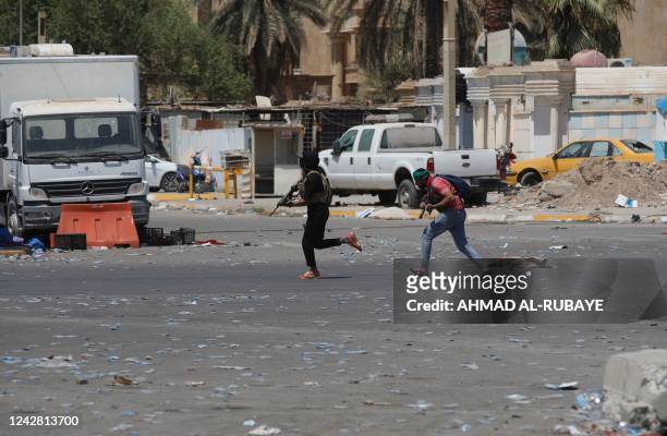 Armed members of Saraya al-Salam , the military wing affiliated with Shiite cleric Moqtada al-Sadr, run for cover during clashes with Iraqi security...