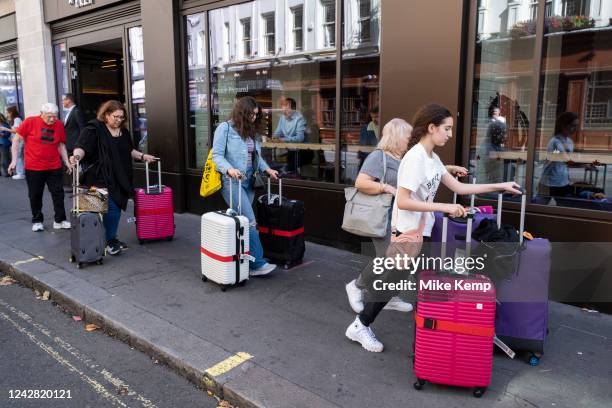 Visitors to London pushing several large suit cases along the pavement on 23rd August 2022 in London, United Kingdom. London is one of the worlds...