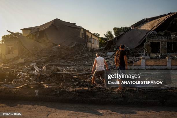 Local residents look at a destroyed school building following a missile strike in Druzhkivka, Donetsk region on August 30 amid the Russian invasion...