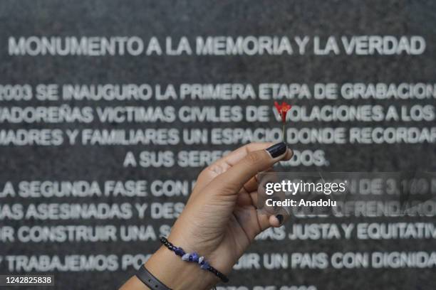 Salvadoran holds a flower by a monument with the names of the victims of the Salvadoran civil war that left at least 8,000 disappeared persons in San...