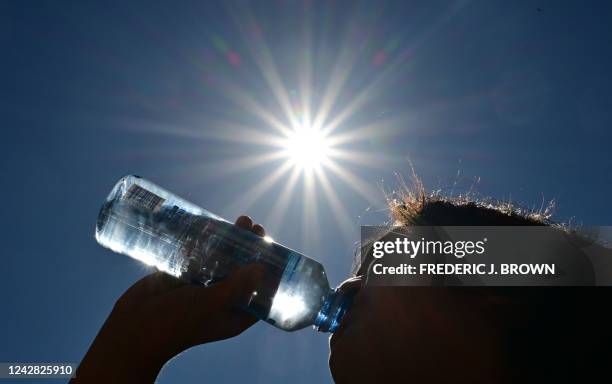 Child sips water from a bottle under a scorching sun on August 30, 2022 in Los Angeles, California. - Forecasters said the mercury could reach as...