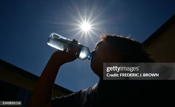 Child sips water from a bottle under a scorching sun on August 30, 2022 in Los Angeles, California. - Forecasters said the mercury could reach as...