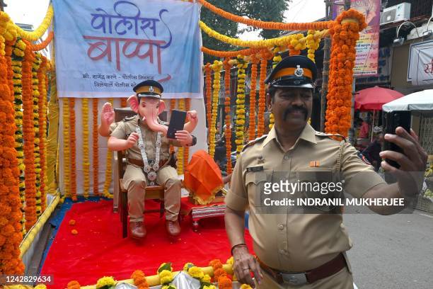 Policeman Rajendra Kane takes a selfie with an idol of the elephant-headed Hindu God Lord Ganesh in the avatar of a policeman during 'Ganesh...