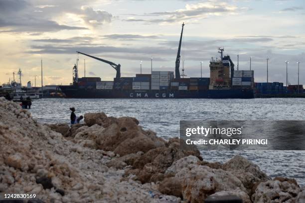 This picture taken on August 30 shows locals staying close to the water as ships dock at the Honiara port. - A snap ban on foreign military vessels...