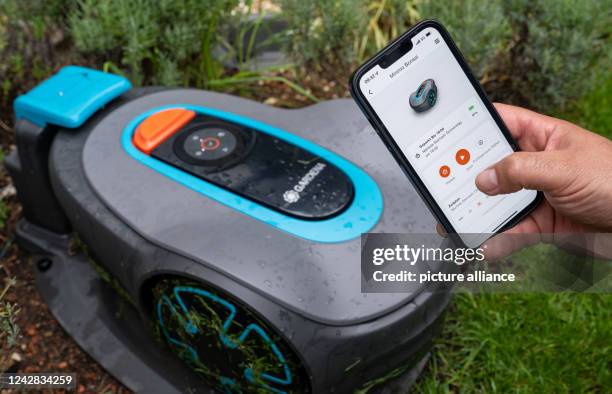 August 2022, Baden-Wuerttemberg, Ulm: A Gardena robotic mower is controlled in its base station with an app on a smartphone. Gardena GmbH, which...