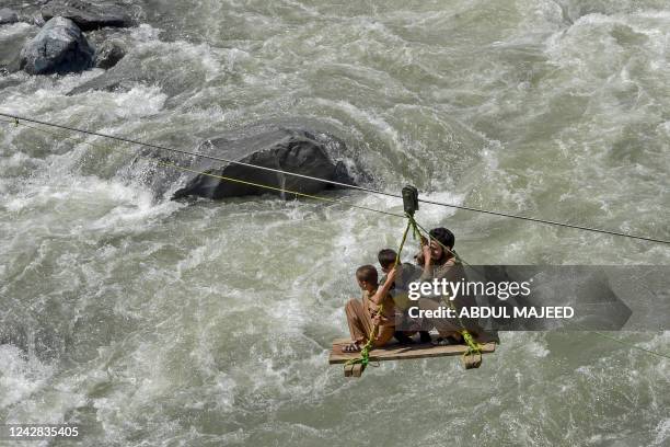 Local residents use a temporary cradle service to cross the river Swat after heavy rains in Bahrain town of Swat valley in Khyber Pakhtunkhwa...