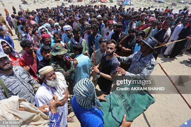 Displaced people who fled from flood-hit areas gather to receive tents from Pakistan's Rangers at Sehwan in Sindh province on August 31, 2022. - Army...