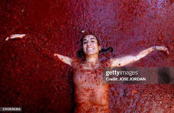 Reveller covered in tomato pulp lies on a crushed tomato flooded street during the annual "Tomatina" festival in the eastern town of Bunol, on August...