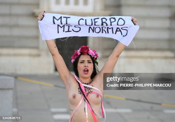 Member of the feminist activist group Femen holds up a banner reading "My body my rules" as she protests with other activists in front of the Royal...