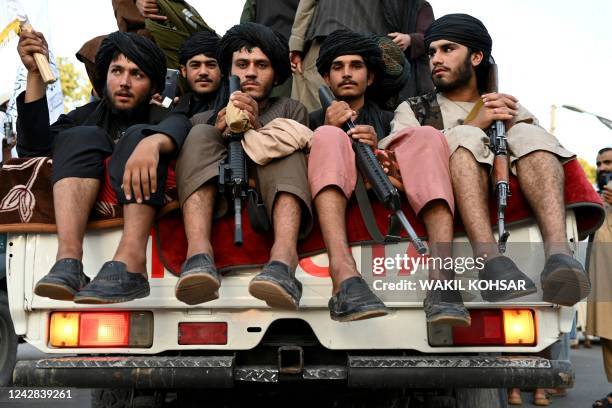 Taliban fighters travel in a vehicle as they celebrate the first anniversary of the withdrawal of US-led troops from Afghanistan, near the airport in...