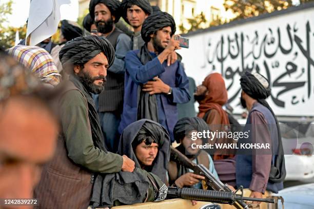 Taliban fighters travel in a vehicle as they celebrate the first anniversary of the withdrawal of US-led troops from Afghanistan, near the airport in...