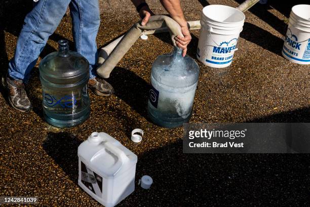 Ty Carter, with Garrett Enterprises, fills jugs with non-potable water at Forest Hill High School on August 31, 2022 in Jackson, Mississippi....