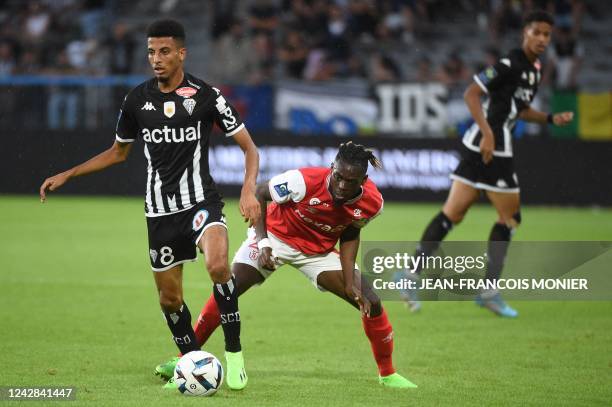 Angers' Moroccan midfielder Azzedine Ounahi is challenged by Reims' French defender Bradley Locko Banzouzi during the French L1 football match...